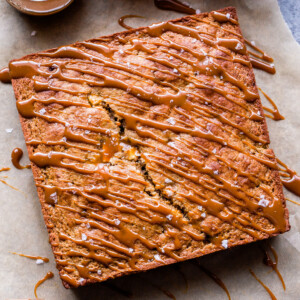 Apple Cake drizzled with Salted Caramel Glaze on parchment paper.