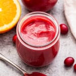 Cranberry Orange Curd in a jar with a spoonful of it in front of the jar