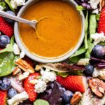 closeup photo of Berries and Feta Salad with a bowl of vinaigrette.