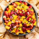 Strawberry Mango Salsa in a bowl surrounded by tortilla chips.