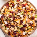 Chicken and Wild Rice Salad in a white bowl with a glass jar of vinaigrette behind it.