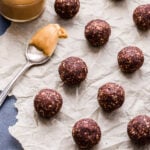 Peanut Butter Mocha Energy Bites on parchment paper with a spoon and jar of peanut butter.