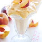 Skinny Peach Milkshake topped with peach slices and a straw.