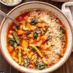 Bowl of minestrone soup with a spoon in it.