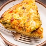 A slice of Crustless Vegetable Quiche on a white plate with a fork.