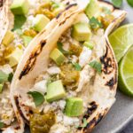 Closeup photo of Creamy Green Chile Chicken Taco topped with crumbled queso fresco, avocado, and cilantro.
