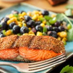 Southwest Grilled Salmon with Blueberry Corn Salsa on the side. On a blue plate with a fork.