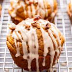 Closeup photo of pumpkin pecan muffins drizzled with bourbon maple glaze and topped with chopped pecans.