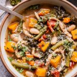 Pesto Chicken and Vegetable Soup in a white bowl with a spoon.
