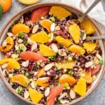 overhead photo of a bowl of Citrus and Wild Rice Salad with serving spoons in the bowl.