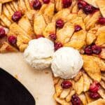 Apple Cranberry Galette with two slices cut out of it and vanilla ice cream on top.