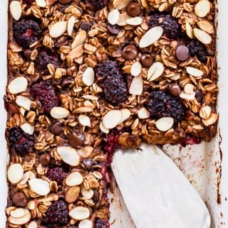 Blackberry Almond Chocolate Chip Baked Oatmeal in white baking dish with a slice cut out.