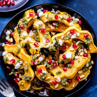Perfectly roasted squash topped with savory, salty and sweet toppings! This Roasted Squash with Pesto, Feta and Pomegranate Seeds is loaded with flavor and the perfect side dish to make this winter! #squash #healthyrecipe #feta #pesto #pomegranate #glutenfree #vegetarian #easyrecipe