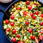 Grilled Zucchini Corn Tomato Salad in black bowl with black serving spoon