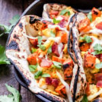 Sweet Potato, Bacon and Egg Breakfast Tacos topped with cheese in a cast iron skillet.