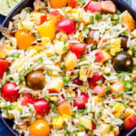 Summer Vegetable Orzo Salad overhead photo in black bowl with limes on the side