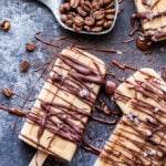 Vanilla Cold Brew Coffee Popsicles drizzled with chocolate. There's a tablespoon of coffee beans behind them.