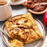 Two pieces of the Apple Sheet Pan Pancake on white plates with maple syrup and apple butter on the table.