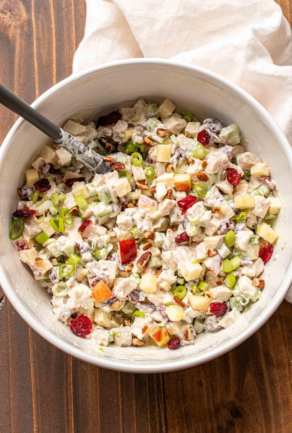 Harvest chicken salad in a white mixing bowl with a rubber spatula in the bowl.