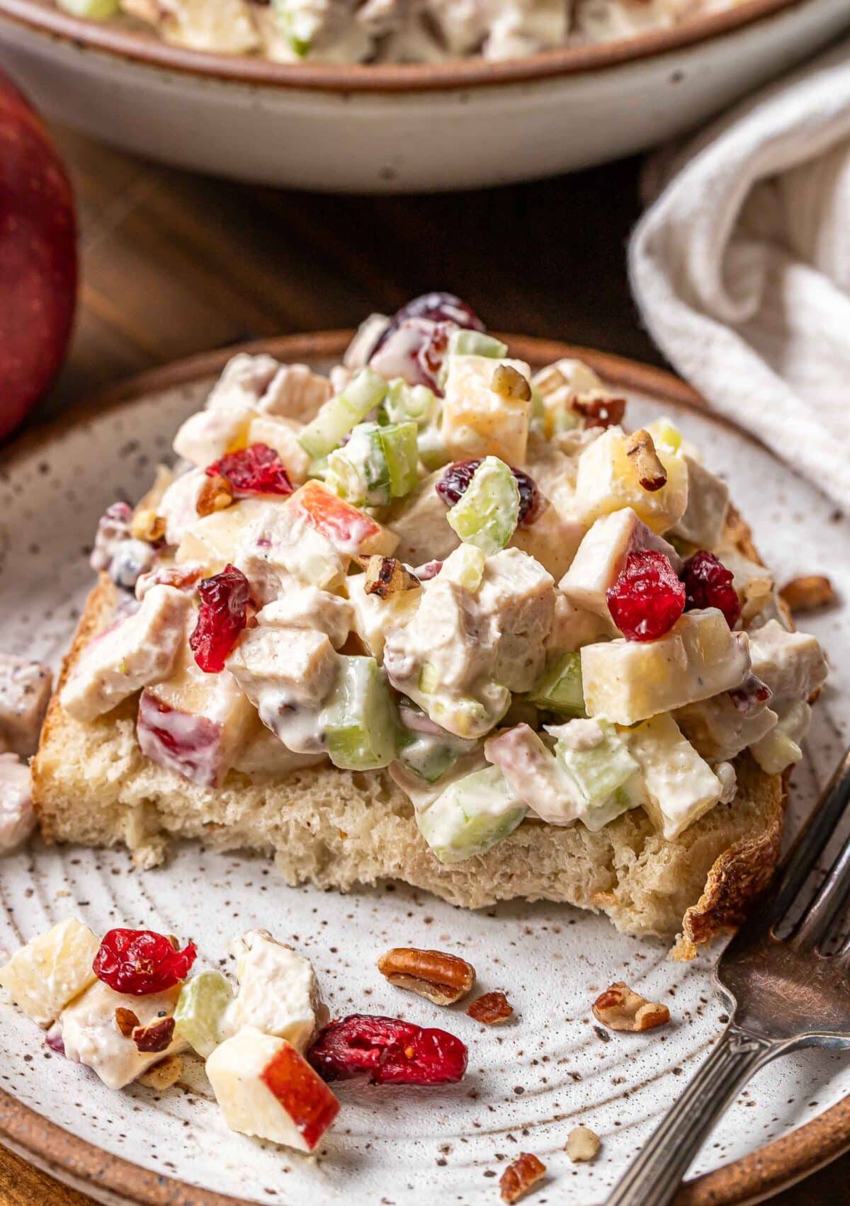 Chicken salad on top of a piece of bread on a white plate.