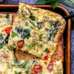 A square sliced of Sheet Pan Spinach Tomato Ricotta Frittata.