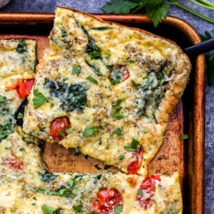 A square sliced of Sheet Pan Spinach Tomato Ricotta Frittata.