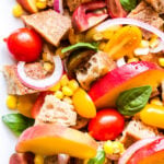 Peach, Tomato and Corn Panzanella on white serving plate