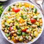 Summer Quinoa Salad in white bowl with chickpeas, corn, tomatoes, cucumbers and basil