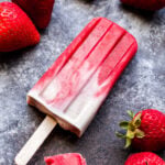 Vegan Strawberries and Cream Popsicle with fresh strawberries next to it.