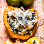 An orange Creamy Chicken, Spinach and Rice Stuffed Pepper topped with melted mozzarella cheese.