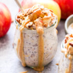 Apple Cinnamon Overnight Oats topped with apples, pecans and almond butter dripping down the side of the glass jar.