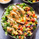 Fiesta Ranch Salad topped with Salsa Verde Chicken slices in a bowl with a side of taco spiced ranch dressing on the side.