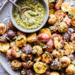 Parmesan Pesto Roasted tri-colored baby Potatoes on a gray plate with a bowl of pesto on the plate.