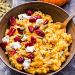 Bowl of Baked Pumpkin Goat Cheese Risotto topped with dried cranberries, pepitas and goat cheese crumbles.