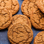 Chewy Ginger Molasses Cookies scattered on blue background.