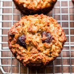 Gluten Free Apple Cinnamon Muffin with dried cranberries on a wire cooling rack.