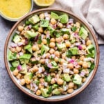 Avocado Chickpea Tuna Salad in round bowl with a small bowl of lemon vinaigrette behind it.