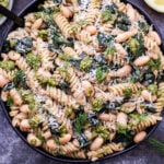 Creamy Kale, White Bean and Pesto Pasta in a black serving bowl with a spoon.