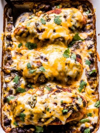 Salsa Verde Baked Chicken on top of black beans and corn. Topped with melted cheese in a casserole dish.