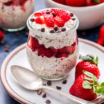 Strawberry Chocolate Chip Overnight Oats in a jar on a white plate with strawberries and mini chocolate chips on the plate.
