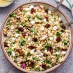 Overhead photo of Sun Dried Tomato Quinoa Salad in serving bowl with feta, pine nuts and parsley.