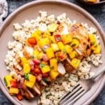 Overhead photo of a plate with rice and a chipotle lime grilled chicken breast topped with mango salsa.