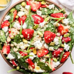 Strawberry Spinach Quinoa Salad with goat cheese and pistachios in a serving bowl.