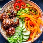 Overhead photo of Asian Turkey Meatball Bowl with chopsticks next to the bowl. Bowl filled with rice, cucumbers, carrots, edamame, jalapenos and five meatballs.