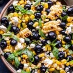 Overhead photo of Blueberry Corn Feta Salad with basil in a white serving bowl.