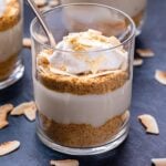 Front view photo of a Coconut Cream Pie Parfait in a glass with a spoon.