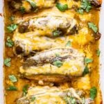 Overhead photo of four chicken breasts in a white rectangular casserole dish. Chicken is baked and covered with green chiles, melted cheese and green enchilada sauce.