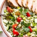Overhead photo of Sliced Greek Lemon Grilled Chicken on top of Cauliflower Tabbouleh in a white bowl.