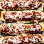 Overhead photo of six Italian stuffed zucchini boats that are filled with ground turkey, marinara sauce and melted mozzarella cheese.