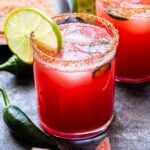 Spicy Watermelon Margarita in a tumbler style glass lined with chili lime salt and a lime wedge.